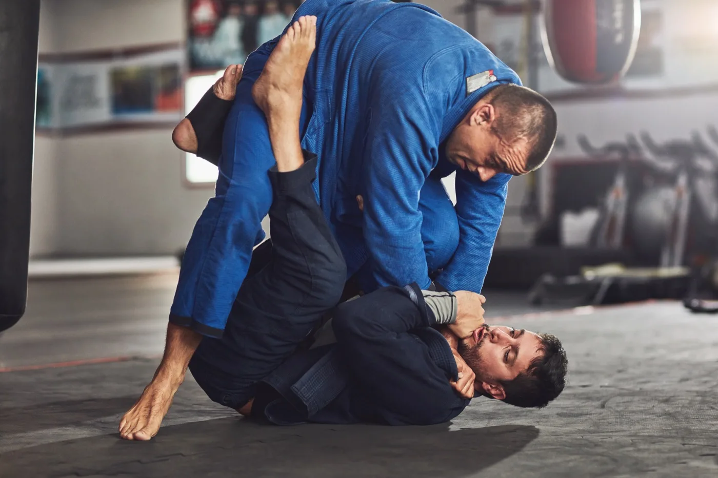 Two fighters rolling in the gi, one passing guard